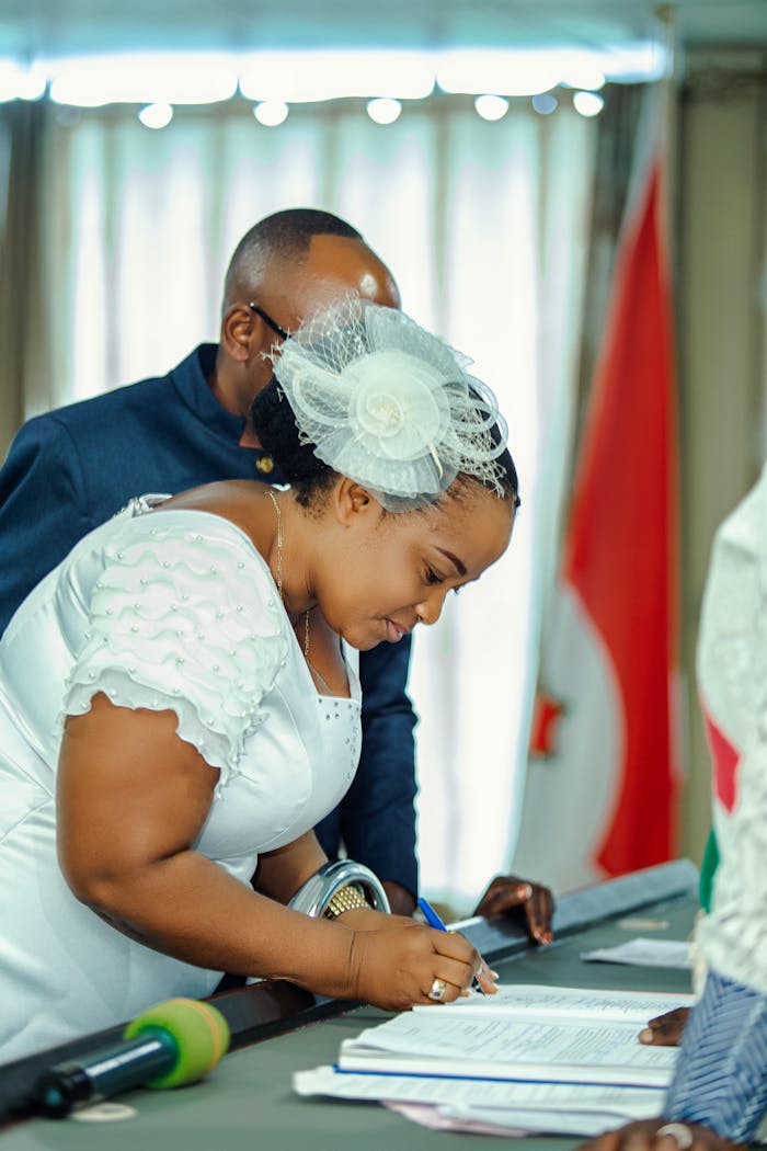 why-choose-us-02 Elegantly dressed individuals participating in an official signing ceremony indoors.
